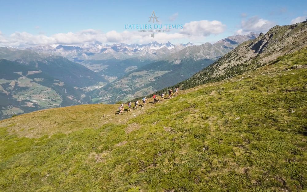 A group of hikers along a Mont Mary trail with a view of the Aosta mountains.